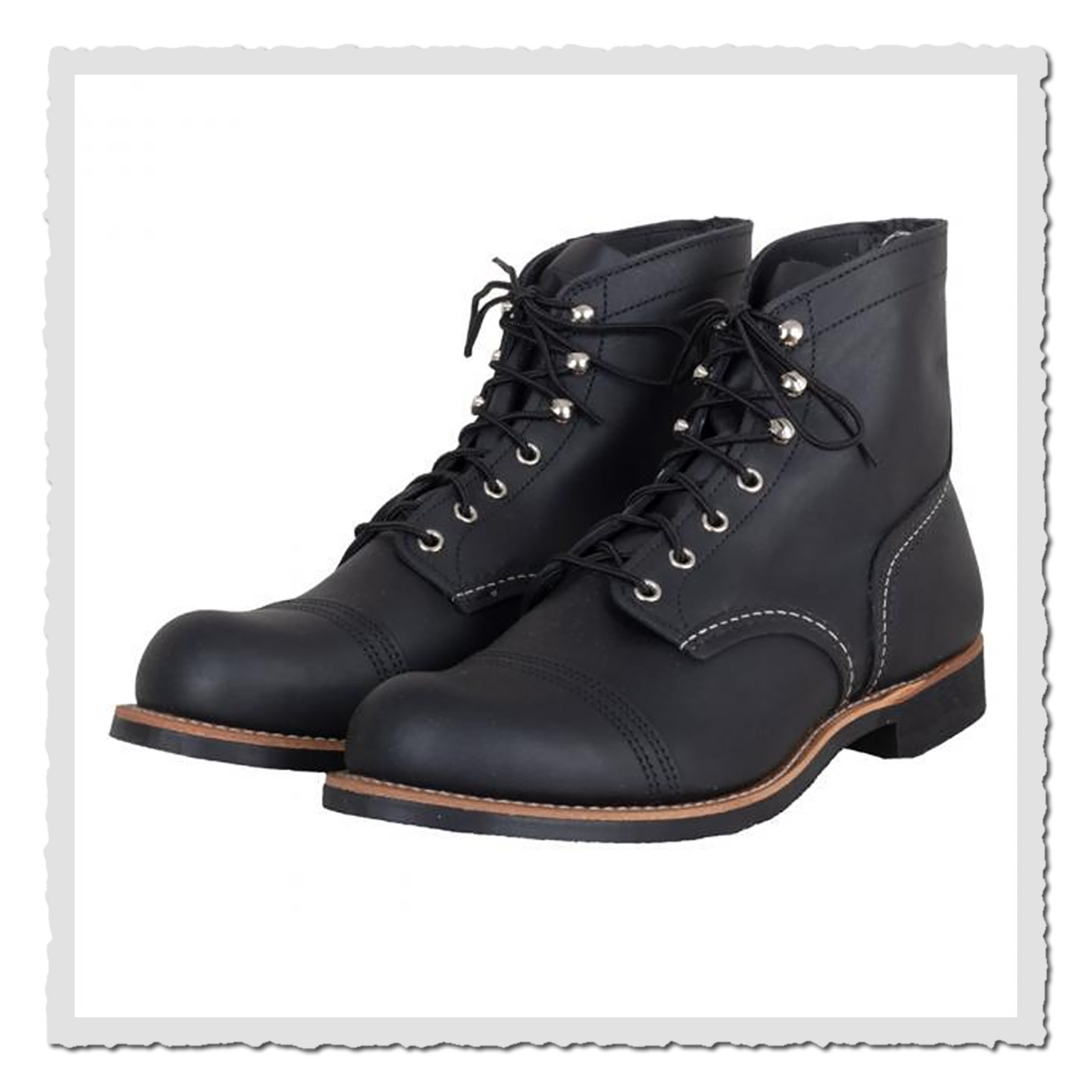 Ein Paar schwarze Lederboots mit sichtbarer Schnürung und Metallösen vor heller Studiofläche.